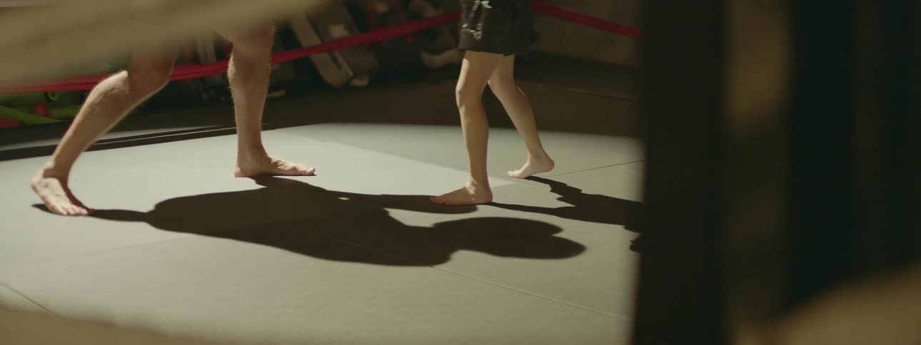 A man and child practicing boxing in a rink