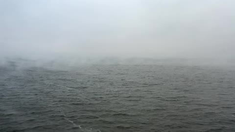 An aerial view of an ocean on a misty day