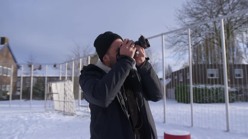 A man stands outside a neighborhood and takes photos with his camera