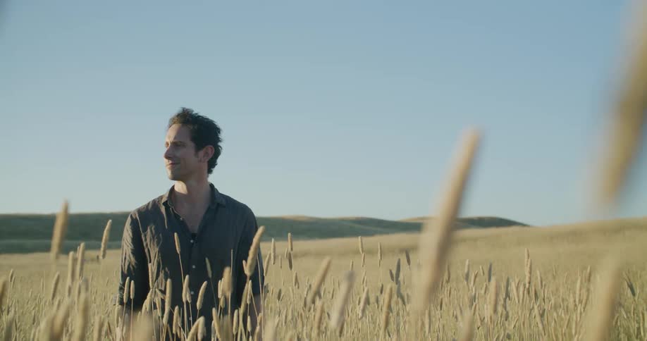 A man stands in a field looking around and smiling
