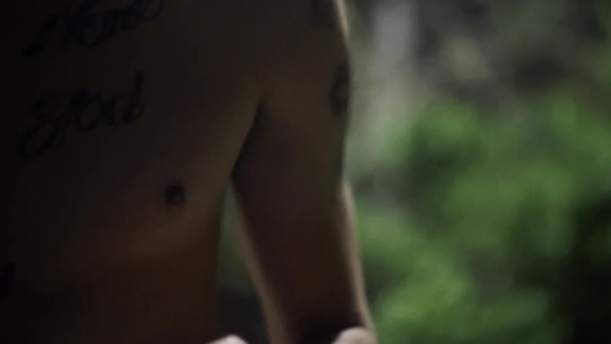 A shirtless man dusts his hands off