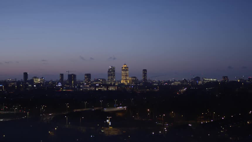 A city skyline with roads and vehicles with the sky and clouds in the background