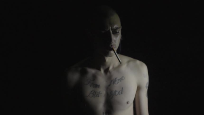 A shirtless man is smoking a cigarette