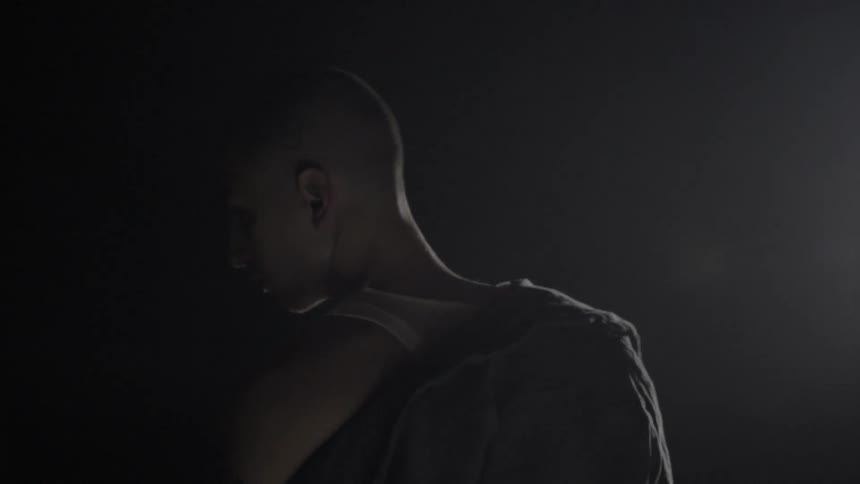 Young man standing in darkness turns