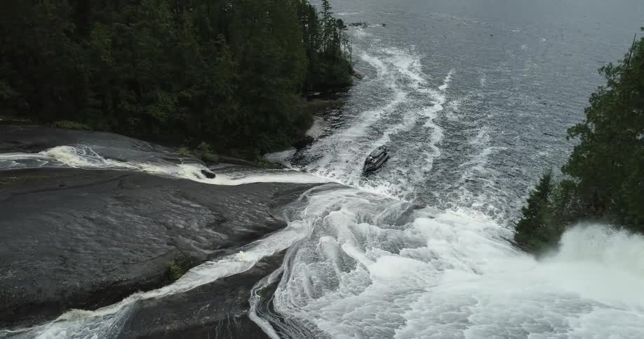 A boat in the bottom of a waterfall surrounded by trees