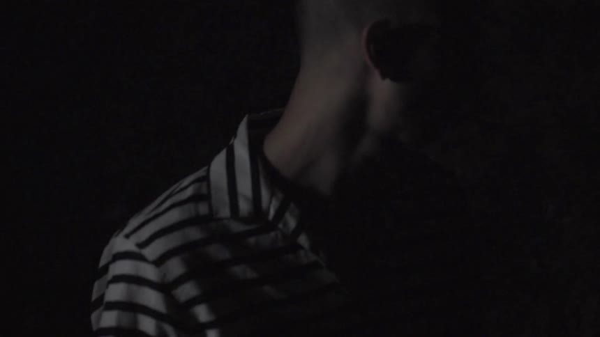 A man wearing pinstripes turns in the dark