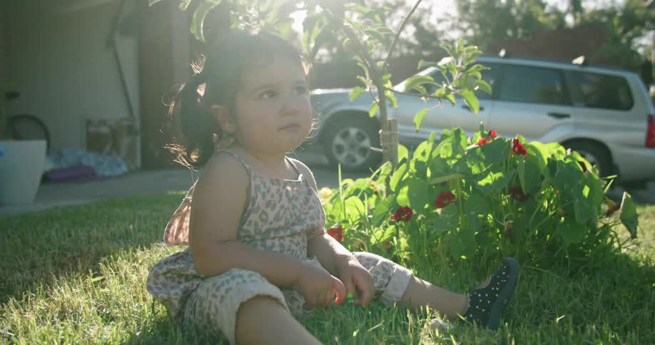 A child is sitting in the grass and playing