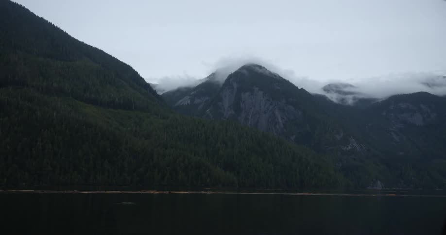 Ocean water moves rapidly in front of a snow topped mountain range
