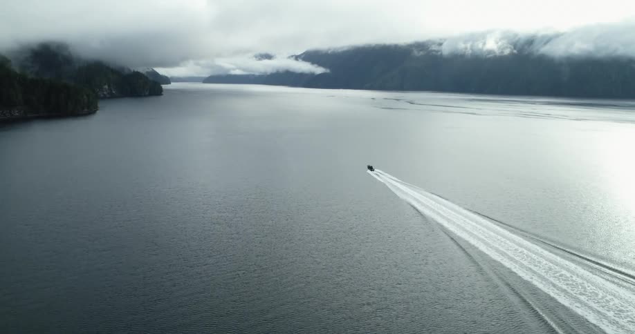 A boat in a river with land the sky and clouds in the background