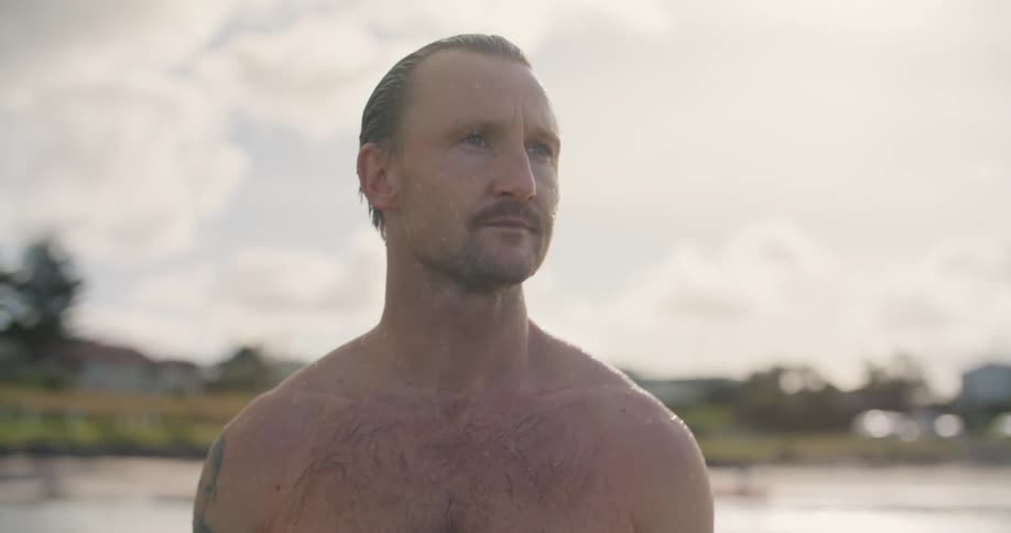 A man is standing in the ocean at dawn