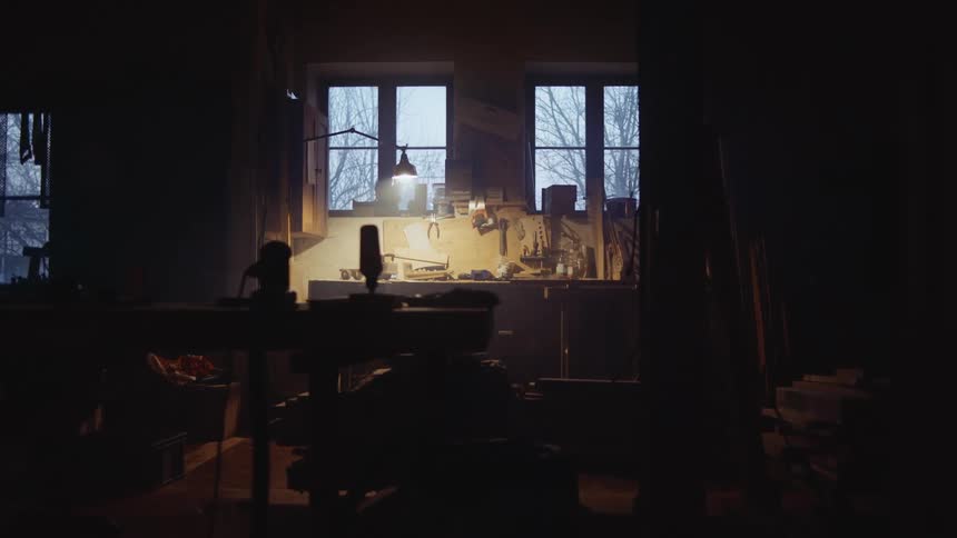 A dark room in a house with a desk and a lamp lit above it