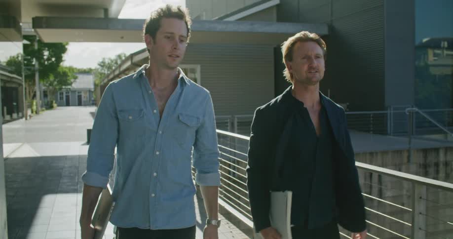 Two men outside an office building talk as they walk