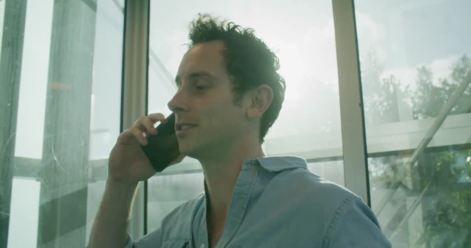 A man talks on his smartphone while riding a glass elevator down