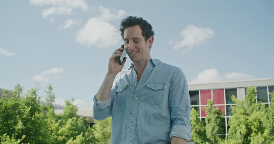 A man is talking on his cellphone and standing outdoors