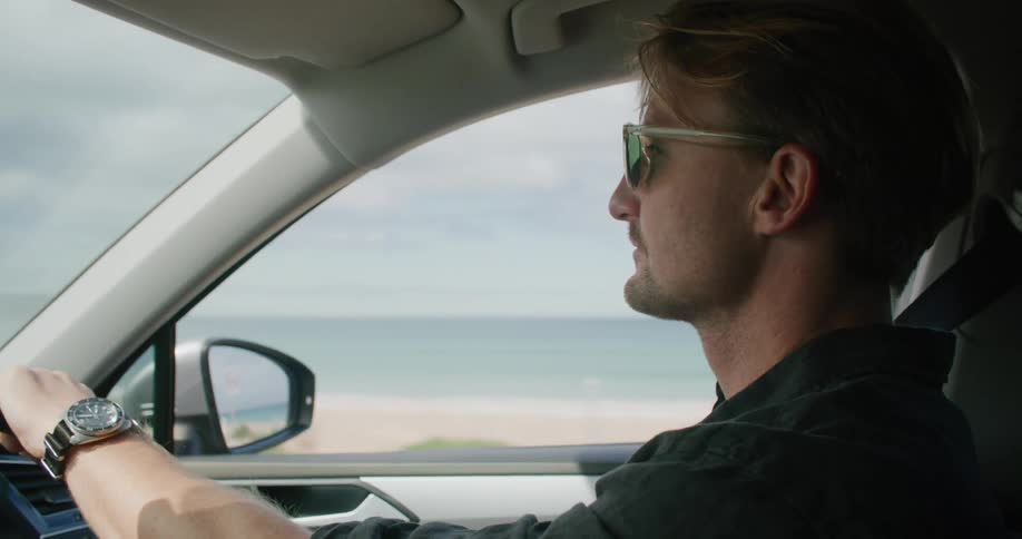 A man driving along a coastline in the daytime