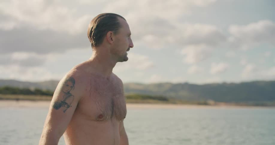 A man is swimming in the ocean water at dusk