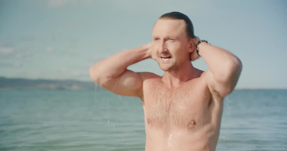 A man walking out of the ocean after swimming
