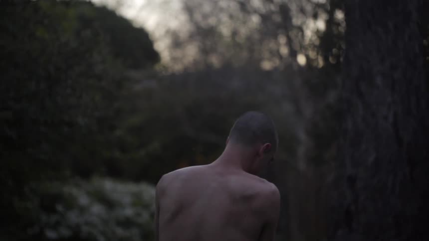 A man slowly takes off his shirt