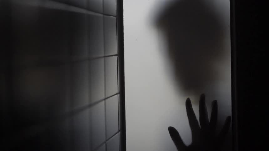 A person's shadow can be seen through frosted glass