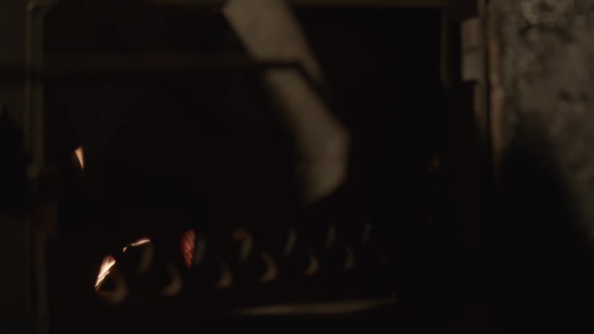 A person closes a cover on a fireplace as a fire burns