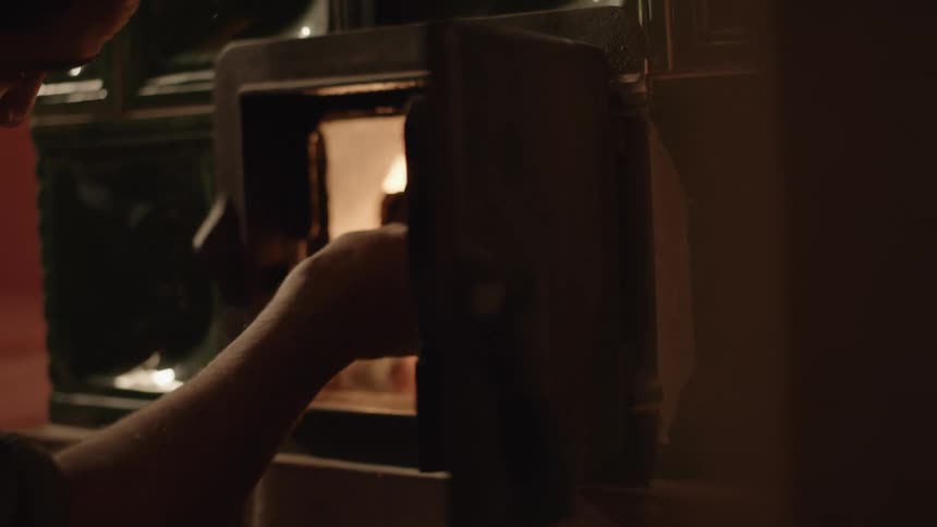 A person that is loading wood into an oven