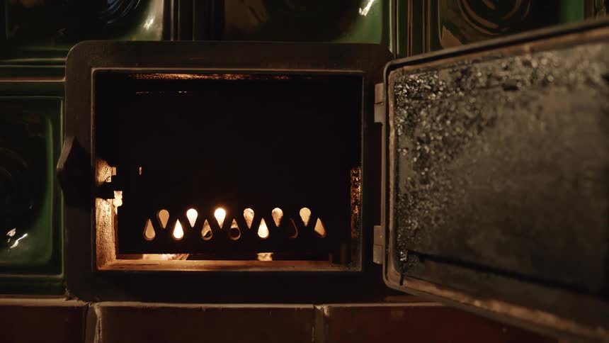 Flames show through grill on door of furnace surrounded by bricks