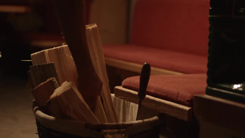 A person is putting wood in a fireplace
