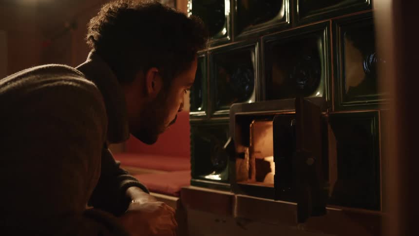 Man examines wood burning furnace before warming his hands