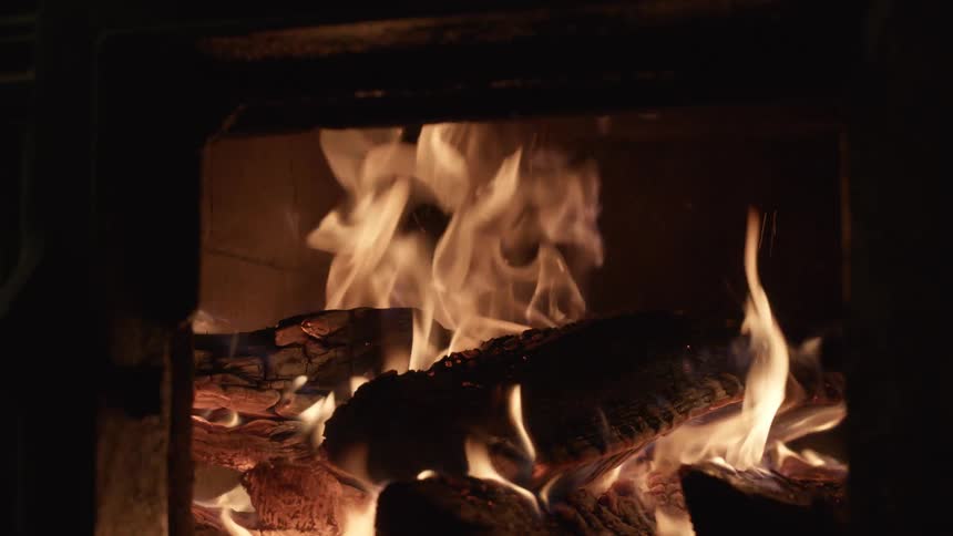 Wood burns in flames inside a fireplace