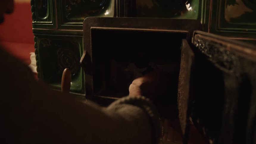 A man lights a match and starts a fire in a fireplace at home
