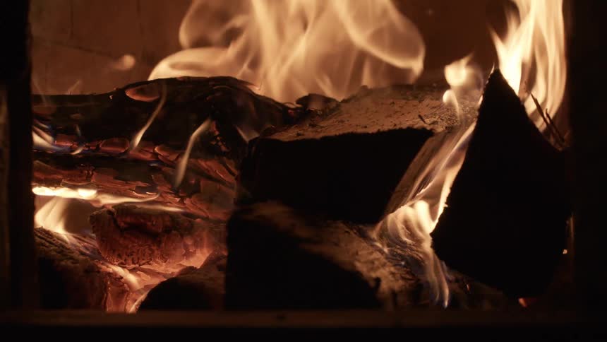 Wood burns in flames inside a fireplace