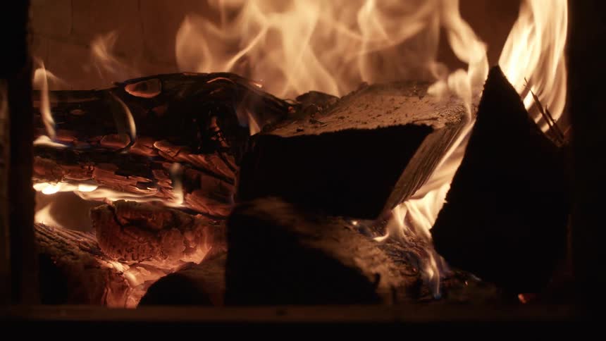 Wood burns in flames inside a fireplace