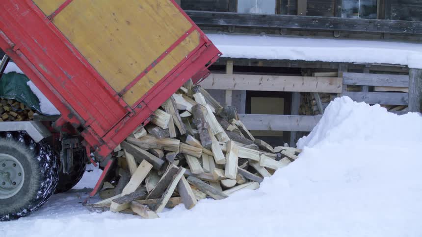 A truck drives forward a bit to completely dump out the firewood it is delivering