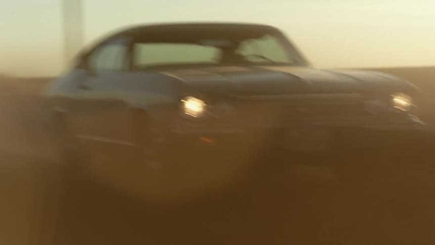 An antique car being driven aggressively on a rural dirt road