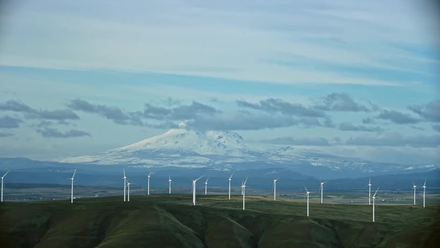 Aerial wide shot of wind turbines spinning with Mount Addams in the background as the camera moves to the right