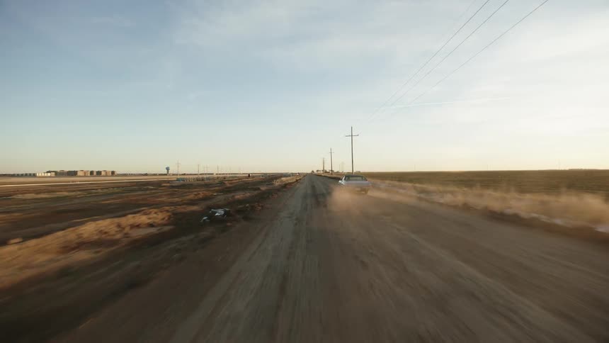 A car is driving in a rural area during the day