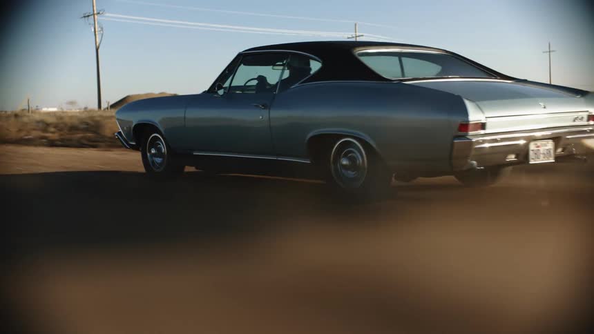 A view of a car driving down a dirt road