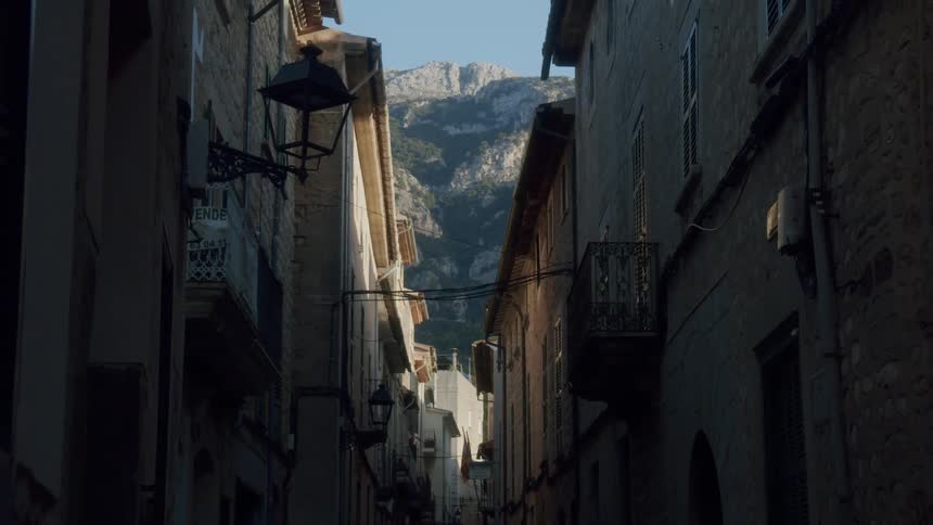 A mountain range is visible through the alley between apartment buildings