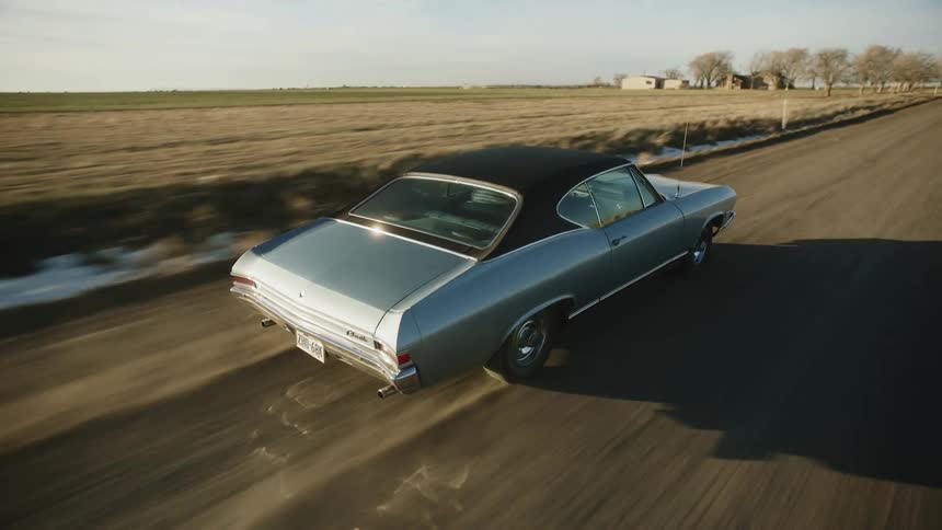 A car is driving on a road in a rural area