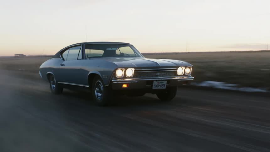 A car is driving on a road in a rural area