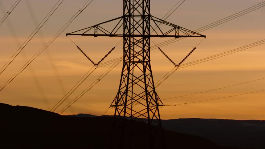 A view of large high tension electrical power lines as the sunsets communicating the complex energy needs of our world
