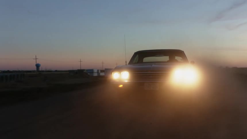 A car is driving on a road at dusk