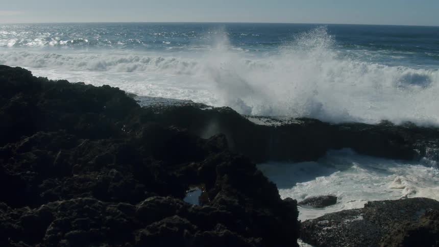 A view of waves crashing against rocks in slow motion