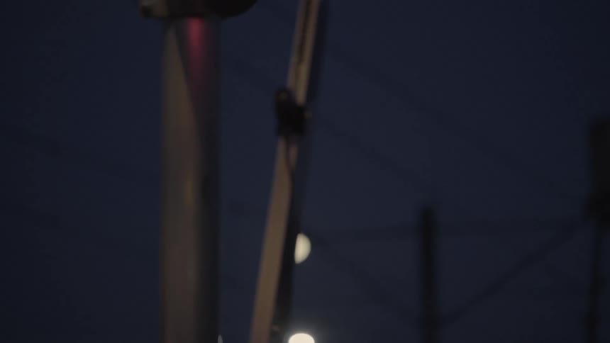 A signal on an arm gate blinks as it raises at night