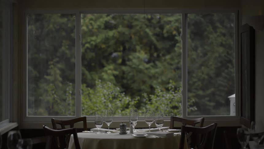 An empty table set for guests sits in front of a picture window in a restaurant