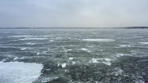 An ocean with water and ice with the sky and clouds in the background
