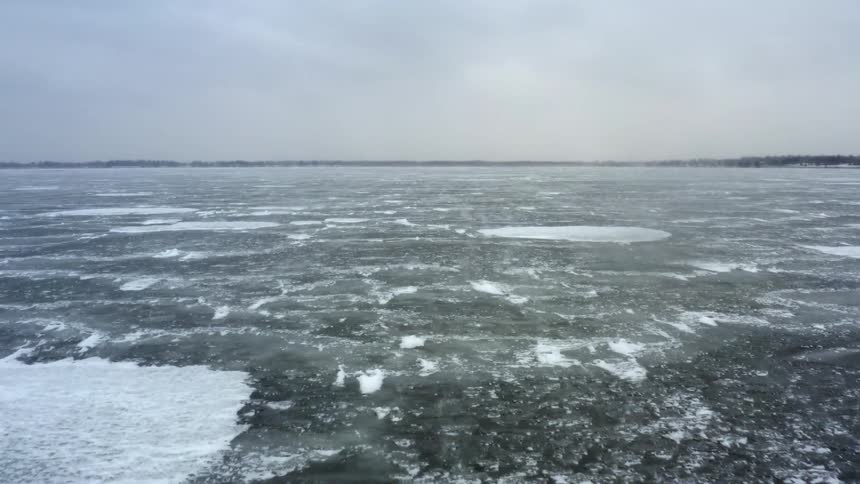 An ocean with water and ice with the sky and clouds in the background