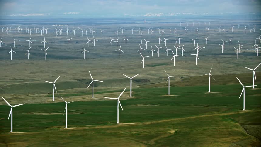 High altitude aerial shot of a massive wind farm generating a lot of renewable energy on farm land in the USA