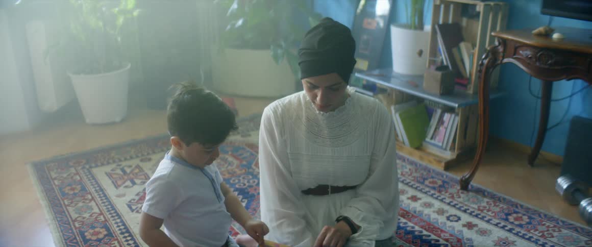 A mother and son read a book together in the living room