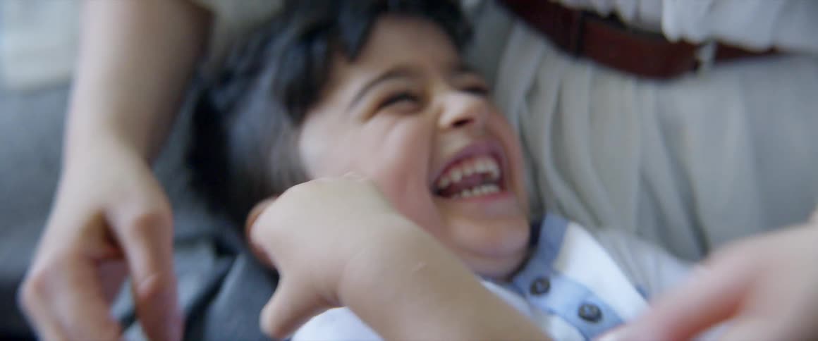 Mother is tickling son in the floor the son is laughing and smiling